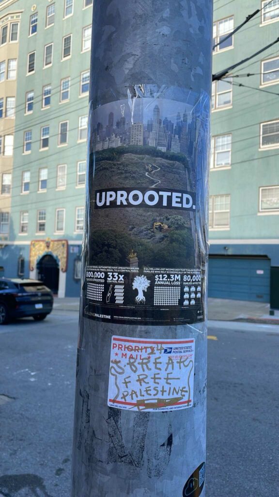 An image of a poster taped to a light post. Large text that says "UPROOTED." is emblazoned over an image of Central Park destroyed by bulldozers. Additional text and graphics below discuss the devastation Palestine has experienced in comparison to Central Park: 800,000 trees uprooted, or 33 times Central Park. A $12.3 annual loss. 80,000 families affected. The poster is part of the Visualizing Palestine project, and there is a link to www.VisualizingPalestine.org at the bottom.