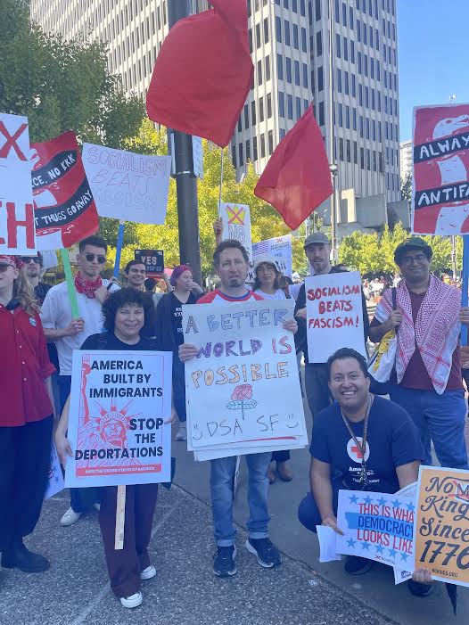Photo of comrades participating in the No Kings Rally and showing off their picket signs